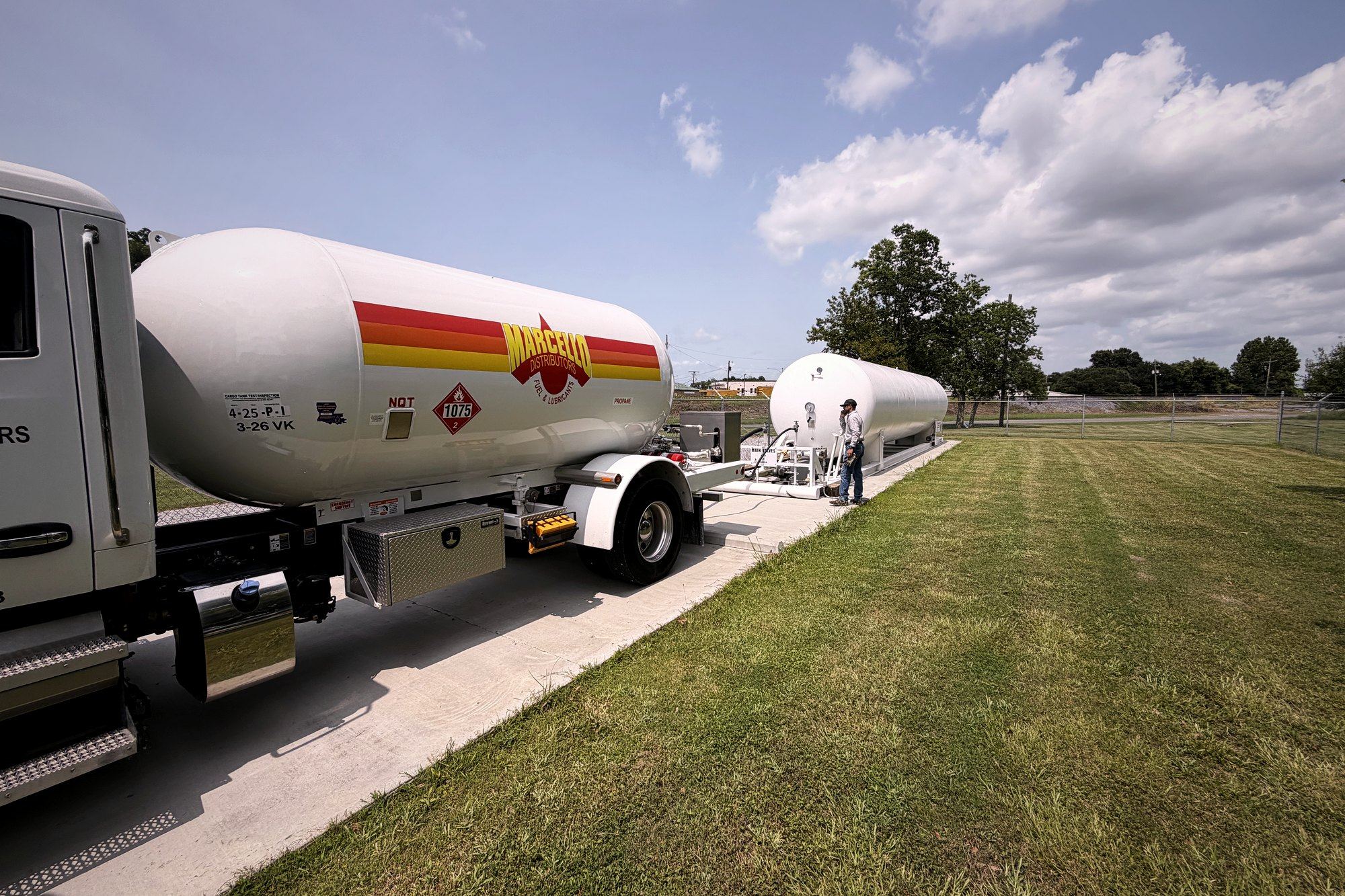 Bobtail tanker delivering fuel to an above-ground tank at a job site
